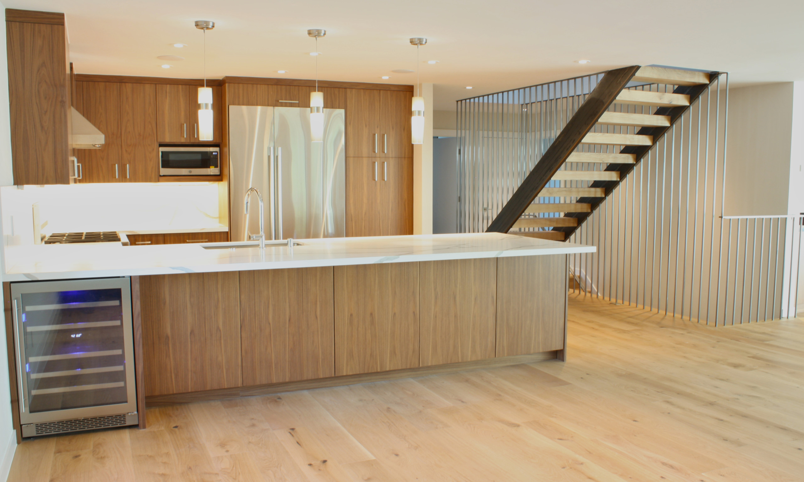 Contemporary open floor plan kitchen with dramatic new stair, custom walnut cabinetry, stainless steel appliances.