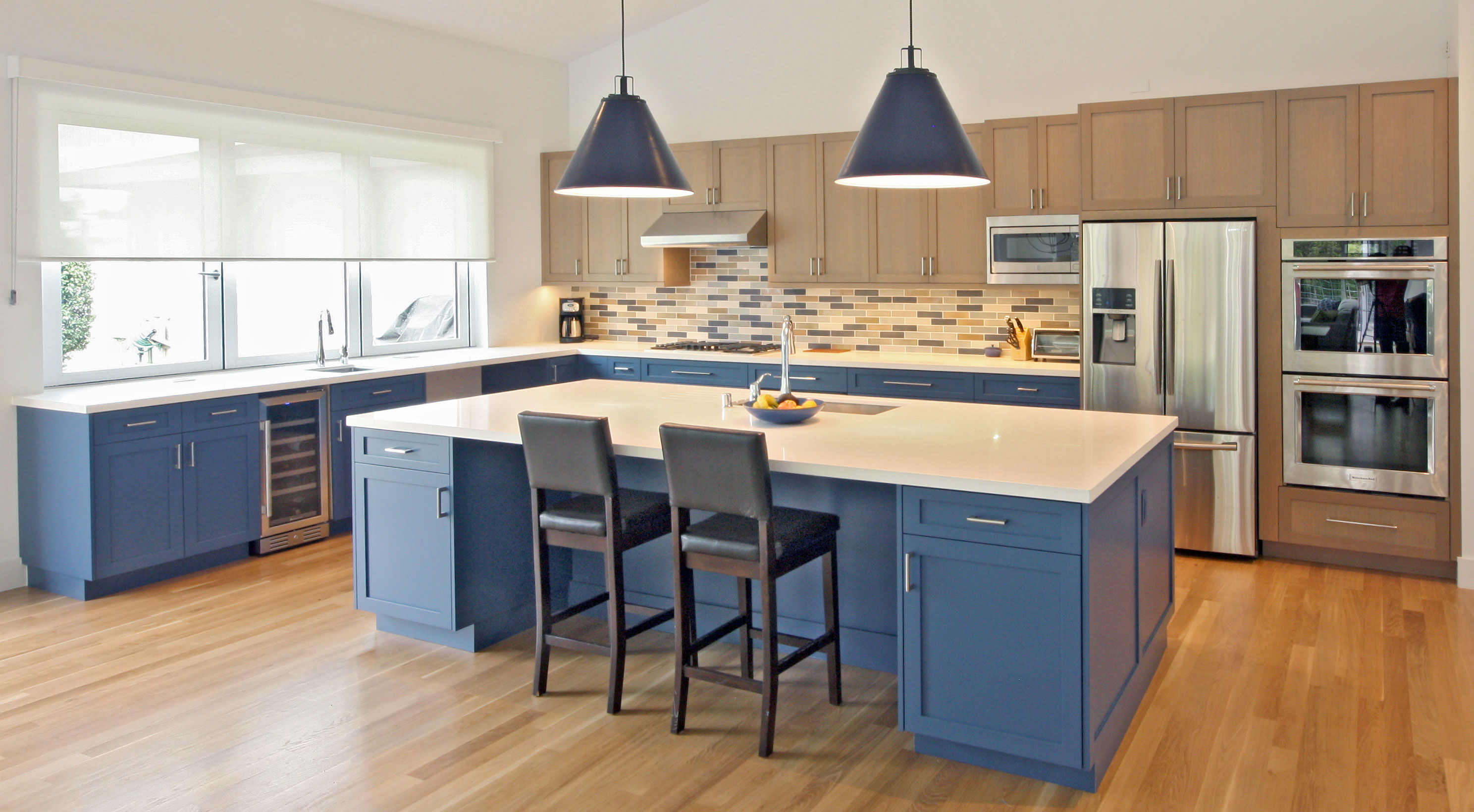 Sonoma Kitchen with large island, two tone cabinetry, blue lower cabinetry, riffed oak upper cabinetry, blue pendants, blue and brown tile.