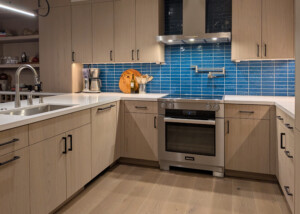 Kitchen with Stainless Steel Range, iridescent blue tile and light wood cabinetry