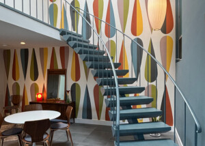 Dramatic sweeping staircase in two story great room with wallpaper.